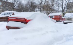 Samochód pod śniegiem stojący na parkingu zimą